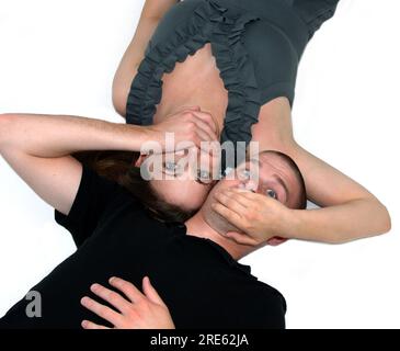 Mann und Frau lagen auf weißem Boden, gegenüberliegend. Jeder hat seine Hände über den Mund des anderen. Konzeptionelle Ideen könnten Geheimnisse sein. Stockfoto