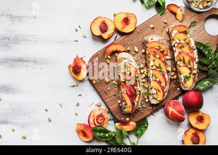 Vom Tisch aus können Sie frischen Vollkorntoast mit Pfirsich und Pistazien mit Ricotta, Basilikum und Honig genießen. Verfügbarer Kopierplatz. Stockfoto