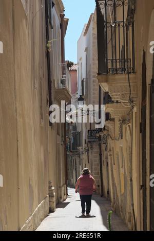 Fette Frau in einer engen Gasse in Ortigia, Siracusa, Sizilien, Italien Stockfoto