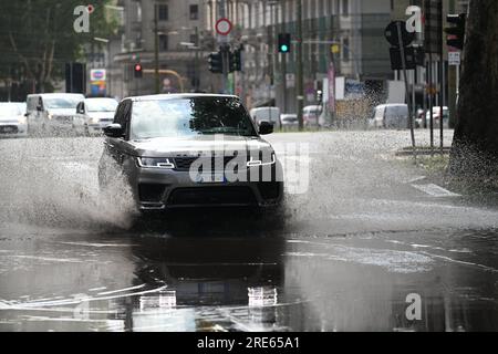 Mailand, Italien. 25. Juli 2023. Am 25. Juli 2023 fährt ein Fahrzeug durch eine überflutete Straße nach einem Gewitter in Mailand, Italien. Während die südlichen zwei Drittel Italiens unter der Hitze der Unterdrückung kämpften, wurde der größte Teil des nördlichen Gebiets von Gewittern und übergroßem Hagel befallen. Medienberichte besagen, dass die Rettungsdienste in Mailand auf mehr als 200 Hilfeersuchen im Zusammenhang mit Überschwemmungen, Baumstürzen und Schäden an Autos und Häusern reagiert haben, da die Stadt am späten Montag von einem schweren Sturm heimgesucht wurde. Kredit: Str/Xinhua/Alamy Live News Stockfoto