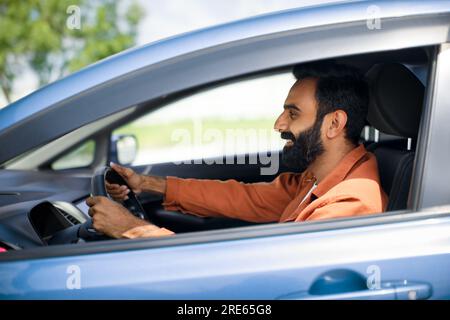 Profilporträt eines lächelnden, bärtigen araber, der im Auto sitzt Stockfoto