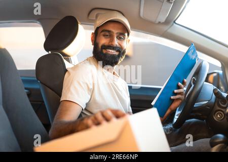 Arabischer Zusteller, Der Auf Den Paketkasten Im Auto Schaut Stockfoto