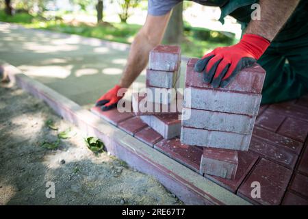 Im Sommer werden Straßenbauarbeiten zum Verlegen eines neuen Fußgängerwegs durchgeführt. Stockfoto