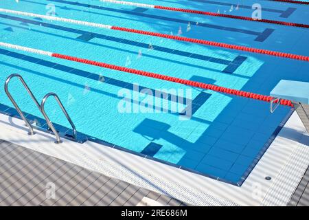 Ein blauer Swimmingpool mit Startplattformen, Markierungen auf den Schwimmwegen, roten schwimmenden Seilbahnen und Startplattformen. Stockfoto