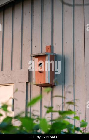 Rot bemaltetes Vogelhaus an der Seite einer Garage Stockfoto