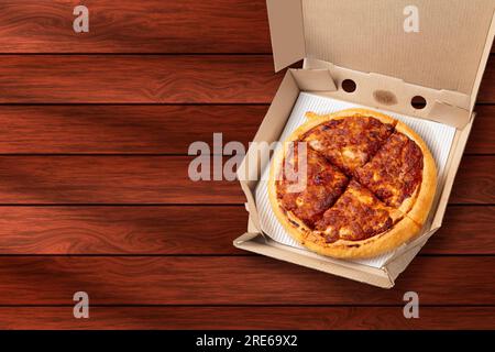 Margherita-Pizza in offener Lieferkarton auf Holzhintergrund. Stockfoto