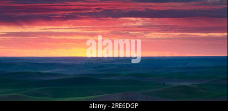 Panoramablick auf die sanften Hügel von Palouse und den Sonnenuntergang am Himmel im Juni. Whitman County, Washington, USA. Stockfoto