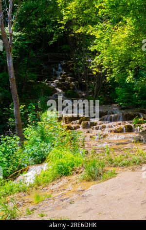 Wagen Sie sich in eine magische Welt der Waldwasserfälle, wo die Kunst der Natur atemberaubende türkisfarbene Seen enthüllt. Tauchen Sie ein in das ruhige B Stockfoto
