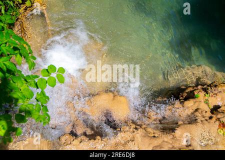 Wagen Sie sich in eine magische Welt der Waldwasserfälle, wo die Kunst der Natur atemberaubende türkisfarbene Seen enthüllt. Tauchen Sie ein in das ruhige B Stockfoto