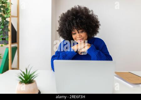 Junge afroamerikanische Frau, die zu Hause an einem Laptop arbeitet. Stockfoto
