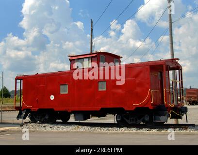 Der rote Kutscher sitzt auf einer abgeschnittenen Strecke in einem Eisenbahnhof in Alabama. Der Himmel ist blau und sonnig. Stockfoto