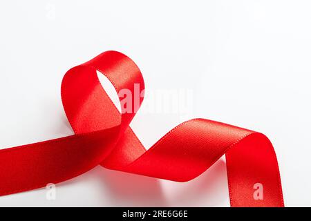 Rotes Seidenband zum Einwickeln von Geschenken auf weißem Hintergrund. Locken aus dekorativem Weihnachtsband. Element für Konstruktion. Stockfoto