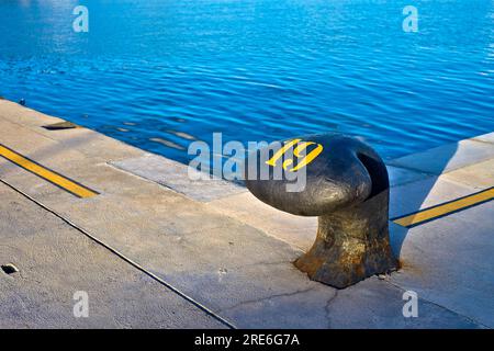 Nummer 19, neunzehn, Schablonen-gelbe Ziffer, gemalt auf einem großen gewerblichen Hafenpfosten. Stockfoto