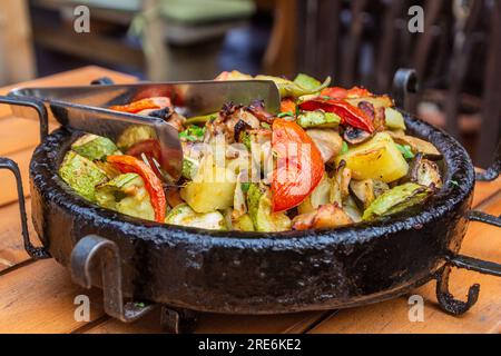 Typisch bulgarisches Essen - Gemüse, das in einem Topf namens sach gebacken wurde Stockfoto