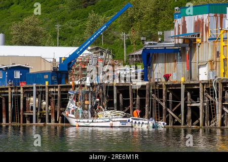 Kodiak, Alaska, USA - 12. Juli 2023: Kommerzielles Lachsfischerboot neben Verarbeitungsbetrieb in St. Paul Harbor in Kodiak, Alaska. Stockfoto