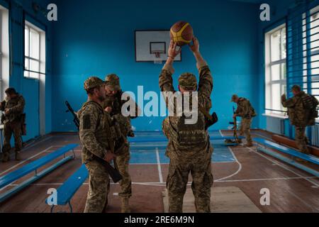 Kiew, Oblast Donezk, Ukraine. 23. Mai 2023. Nach Abschluss des Kampftrainings spielen ukrainische Soldaten in einer örtlichen Schule Basketball. Die Mitglieder der territorialen Verteidigung Kiews wurden vor kurzem in das Donezbecken entsandt und werden die Ausbildung für die Frontlinien fortsetzen. (Kreditbild: © Madeleine Kelly/ZUMA Press Wire) NUR REDAKTIONELLE VERWENDUNG! Nicht für den kommerziellen GEBRAUCH! Stockfoto