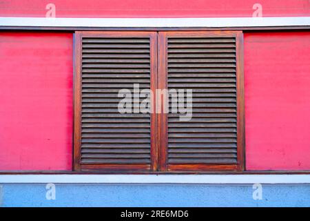 Geschlossene Holzläden mit rosafarbenen Wänden, architektonische Details. Stockfoto