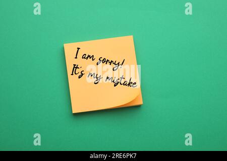 Orangefarbene Haftnotiz mit dem Ausdruck „I am Sorry, IT's My Error“ auf grünem Hintergrund, Draufsicht Stockfoto