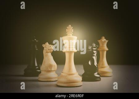 Verschiedene Schachfiguren auf einem grauen Tisch vor dunklem Hintergrund Stockfoto