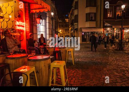 Hocker, ein Tisch und ein Neonschild auf Kopfsteinpflaster vor einer Weinbar in Plovdiv, Bulgarien Stockfoto