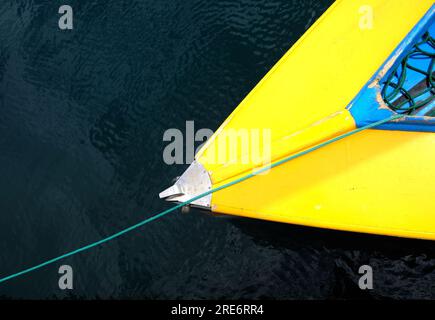 Schleifendetail eines einfachen Holzboots mit hellblauem Cockpit. Draufsicht auf ein kleines Boot auf einem ruhigen Wasser. Stockfoto