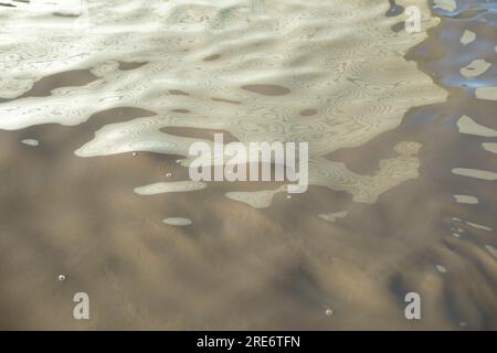 Schmutziges Wasser. Pfützentextur. Trübe Flüssigkeit. Wellen auf der Oberfläche. Stockfoto