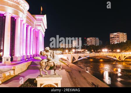 Das hell erleuchtete Archäologiemuseum am Ufer des Vardar in Skopje, Nordmazedonien Stockfoto