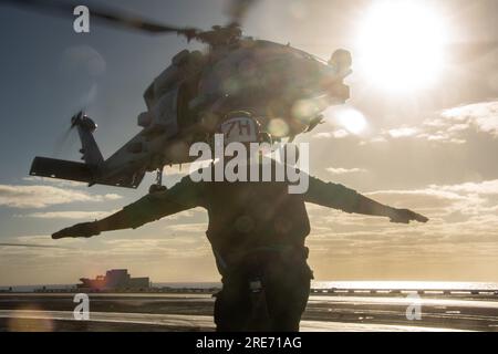 INDIAN OCEAN (25. Juli 2023) Aviation Structural Mechanic Airman Emmanuel Wilkins aus Chicago leitet einen MH-60R Sea Hawk, der an die Saberhawks des Helicopter Maritime Strike Squadron (HSM) 77 angeschlossen ist, während er vom Flugdeck der USA startet Der einzige Flugzeugträger der Navy, USS Ronald Reagan (CVN 76), während des Flugbetriebs zur Unterstützung von Talisman Sabre 23 im Indischen Ozean, am 25. Juli 2023. Ronald Reagan, das Flaggschiff der Carrier Strike Group 5, stellt eine kampfbereite Truppe bereit, die die Vereinigten Staaten schützt und verteidigt und Bündnisse, Partnerschaften und Kollektivbündnisse unterstützt Stockfoto