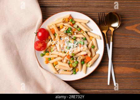 Teller mit leckerem Nudelsalat auf Holzhintergrund Stockfoto