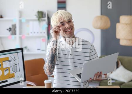 Tätowierter Grafikdesigner, der mit einem Laptop im Büro arbeitet Stockfoto
