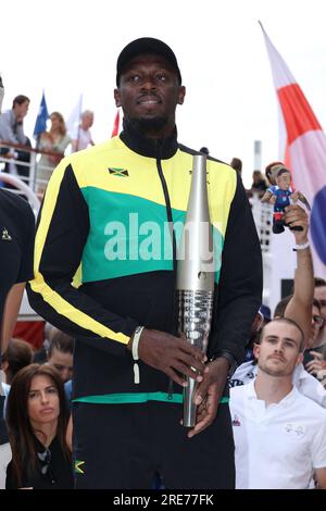 Usain Bolt posiert am 25. Juli 2023 mit der Paralympischen und Olympischen Fackel 2024 in der Nähe des Eiffelturms am Ufer von Paris, Frankreich, während einer Reise auf der seine mit französischen Sportlern, um die offizielle Fackel für 2024 zu präsentieren.Foto von Jerome Domine/ABACAPRESS.COM Kredit: Abaca Press/Alamy Live News Stockfoto