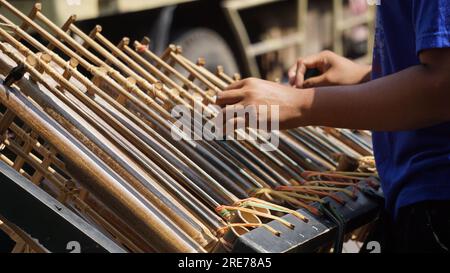 Ein Mann spielt Anglung. Das ist ein mehrfarbiges Musikinstrument, das sich aus den Sundanesen entwickelt hat. Angklung ist aus Bambus Stockfoto