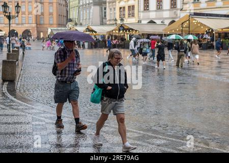 Prag, Tschechische Republik. 25. Juli 2023. Ein älteres Paar spaziert mit einem Regenschirm, der während des starken Regens am Altstädter Ring in Prag zu sehen ist. Mehr als 15 Millimeter Regen in 24 Stunden endete in der aktuellen Trockenzeit in der Tschechischen Republik. Kredit: SOPA Images Limited/Alamy Live News Stockfoto