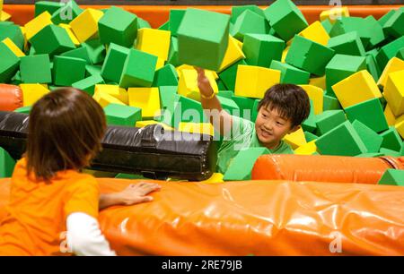 Santa Ana, Kalifornien, USA. 19. November 2016. Ein asiatisch amerikanischer Junge hüpft inmitten von Haufen Schaumgummiblöcken in einem Trampolinpark in Costa Mesa, CA, nachdem er von der X-Beam Balance Attraktion seines Bruders abgeschossen wurde. Schaumgummi-Schläger beachten. (Kreditbild: © Spencer Grant/ZUMA Press Wire) NUR REDAKTIONELLE VERWENDUNG! Nicht für den kommerziellen GEBRAUCH! Stockfoto