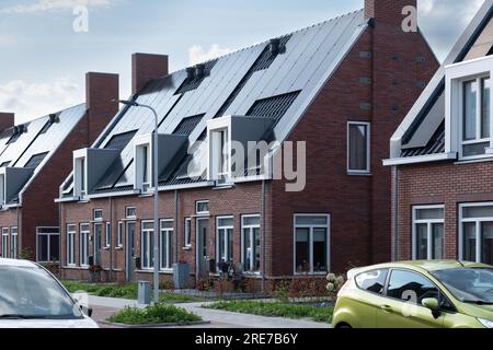 Straße mit modernen Einfamilienhäusern mit Sonnenkollektoren auf dem Dach in den Niederlanden. Nachhaltige Energie. Stromerzeugung Stockfoto