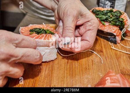 Der Küchenchef bereitet Lachs mit Spinat und gebackener Zitrone und Sauce zu. Französische Gourmetküche. Stockfoto