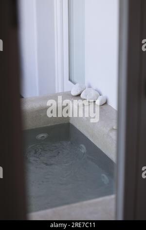 Dekoration entspannende weiße Kopfsteinpflastersteine an der Ecke eines winzigen einheimischen Swimmingpools Stockfoto