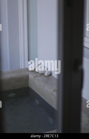 Dekoration entspannende weiße Kopfsteinpflastersteine an der Ecke eines winzigen einheimischen Swimmingpools Stockfoto