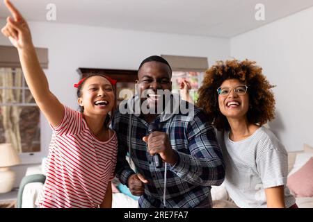 Porträt von fröhlichen, vielfältigen Freunden, die zu Hause tanzen und singen Stockfoto
