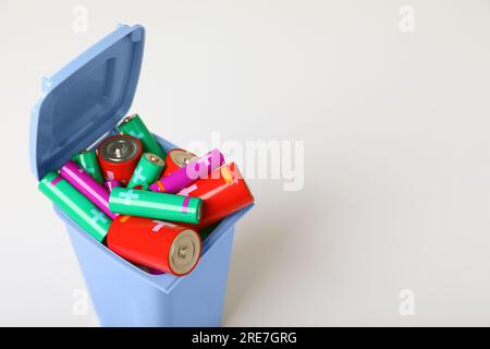 Viele Altbatterien in einem weiß isolierten Recyclingbehälter Stockfoto