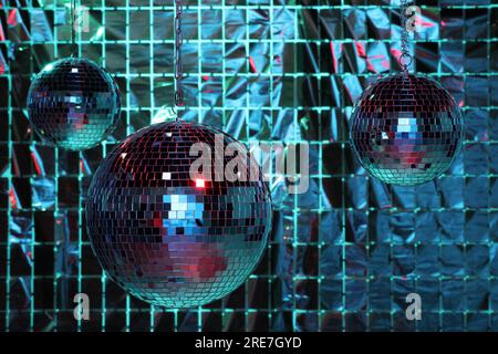 Glänzende Disco-Bälle gegen einen Partyvorhang unter farbigen Lichtern Stockfoto