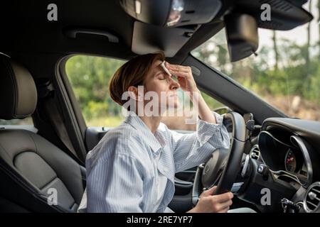 Frau fährt Auto mit kaputter Klimaanlage bei heißem Sommerwetter. Zum Wischen von Schweißpapierservietten. Stockfoto