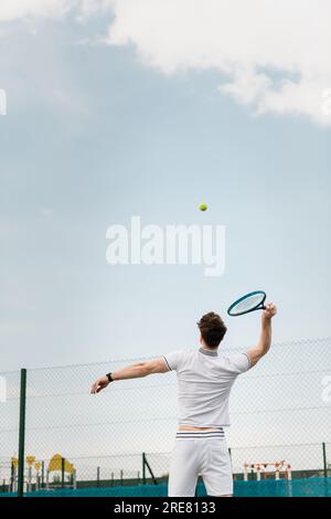 Rückansicht eines Mannes, der Tennis auf dem Platz spielt, Schläger hält, Ball schlägt, Rückhand Stockfoto