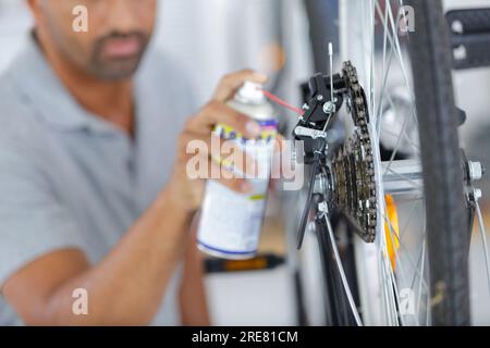 Ein Mann sprüht ein Öl auf eine Fahrradkette Stockfoto