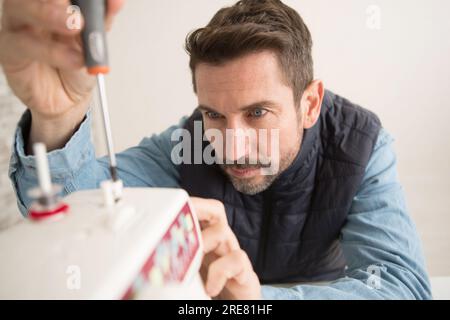 Ein Mann, der beim Vögeln eine Schraubmaschine hält Stockfoto