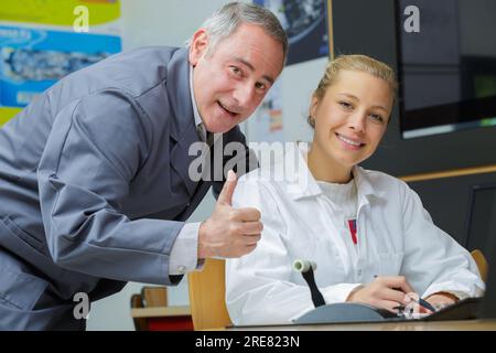 Fröhlicher Trainer mit Auszubildender in der Werkstatt Stockfoto