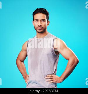 Porträt, Fitness und selbstbewusster asiatischer Männerschweiss im Studio isoliert auf blauem Hintergrund. Gesichts-, ernsthafte und persönliche Trainerin mit Übung, Training oder Stockfoto
