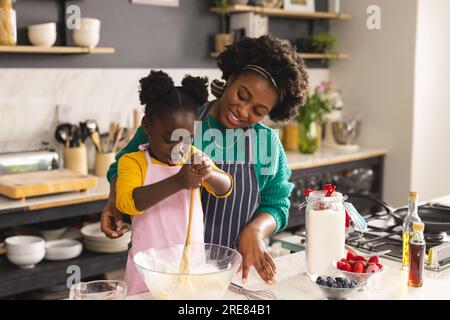 Glückliche afroamerikanische Mutter und Tochter backen Pfannkuchen in der Küche zu Hause Stockfoto