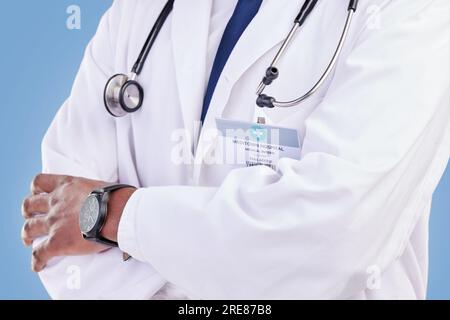 Arzt, Stethoskop und Arme gekreuzt im Studio mit einem medizinischen Experten oder Gesundheitspersonal auf blauem Hintergrund. Chirurg, Hände und Vertrauen in Stockfoto