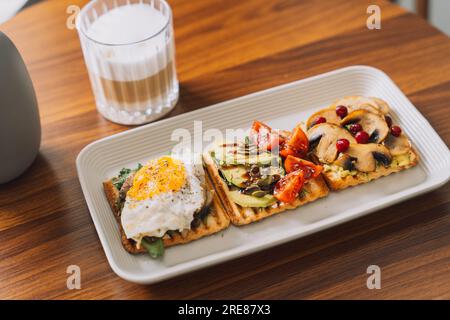 Zum Frühstück gibt es Toasts mit verschiedenen Belägen und eine Tasse Kaffee Stockfoto